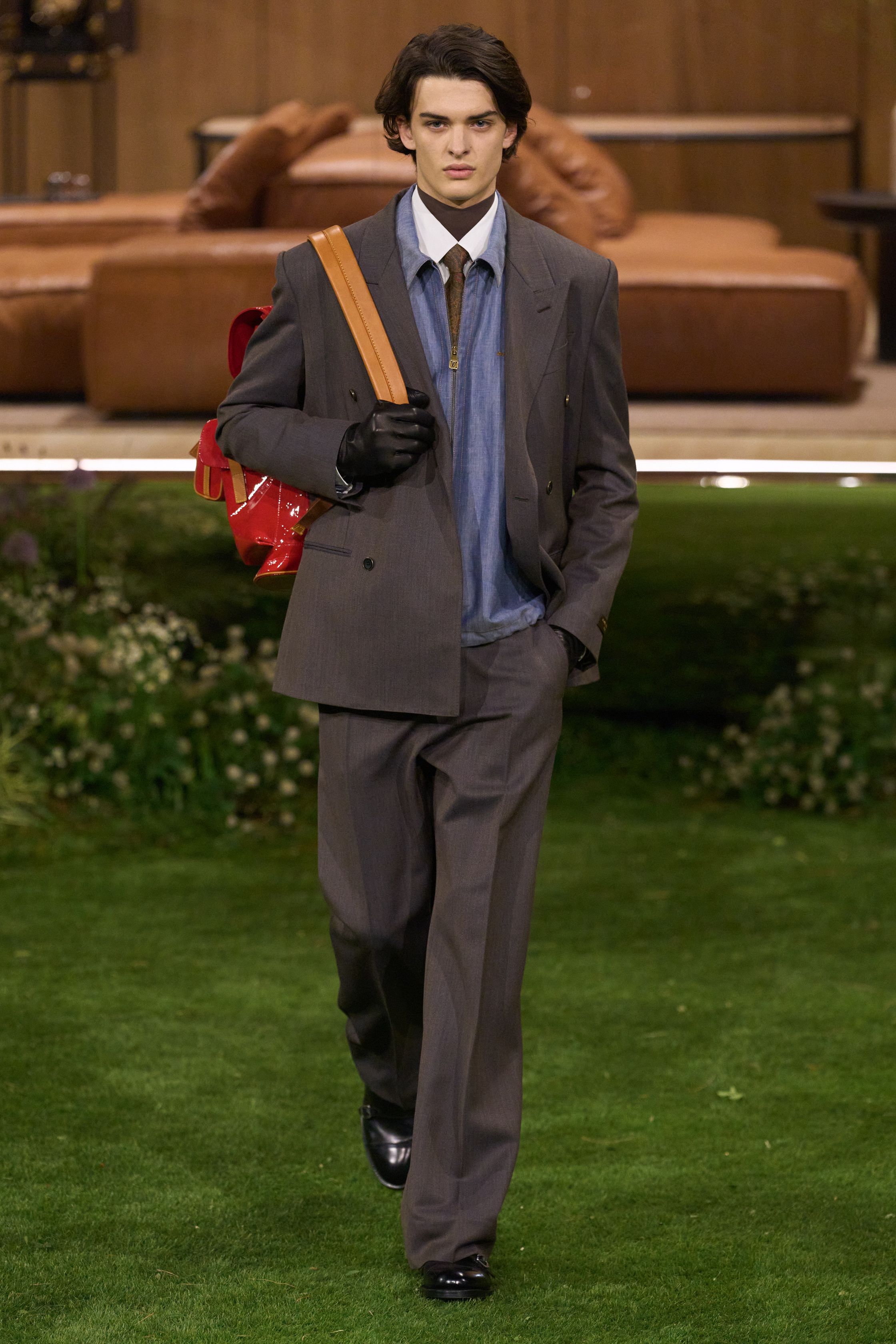 Louis Vuitton 26FW 男装以“当代绅士的旅行状态”为核心，在花园式场景中展开一场关于移动、身份与功能的叙事。功能夹克、细致西装、学院感针织与标志性包袋并行出现，色彩回归卡其、橄榄绿、灰褐与深红，呈现出低调却高度可穿的奢华现实主义。系列强化了“穿着中的生活感”，将品牌传统的旅行基因转译为更克制、更日常的现代衣橱方案-顽石频道趋势研究